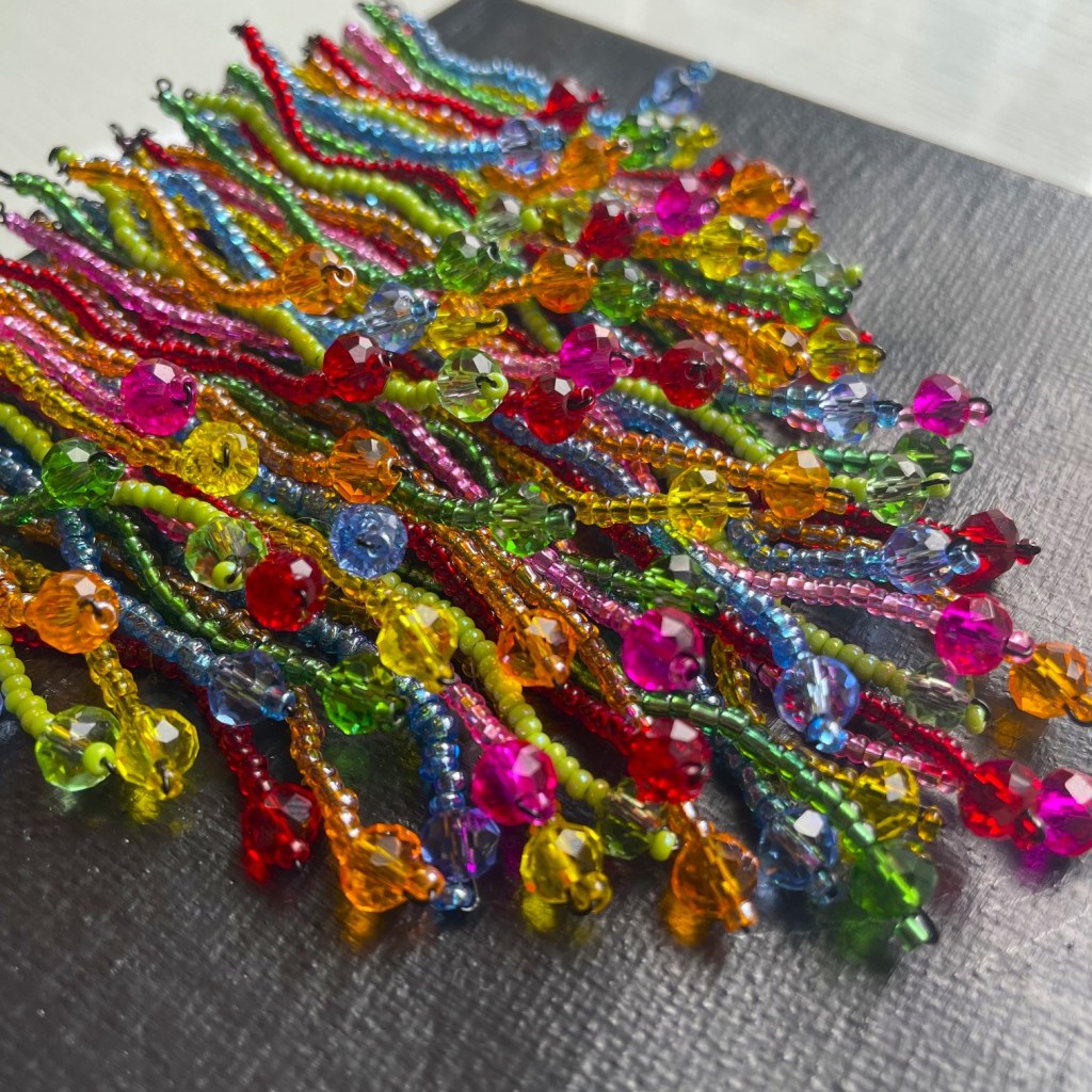 Close-up of colorful beaded strands featuring a variety of bright beads in red, green, yellow, pink, and blue.